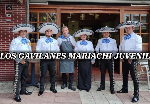 Mariachis vestidos con atuendos blancos y negros con el dueño del negocio
